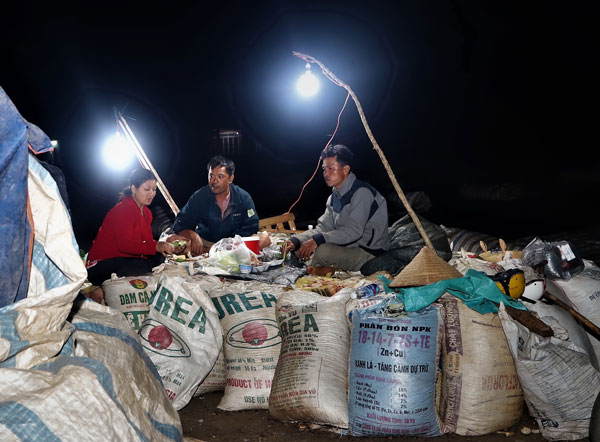 Trên một bãi phơi rộng lớn, những người nông dân xã Lộc Đức, huyện Bảo Lâm ăn vội bữa tối sau một ngày lao động mệt nhoài để lấy sức tiếp tục cho công việc nặng nhọc không kém tiếp theo - thức sáng đêm để canh giữ cà phê. Ảnh: K.Phúc