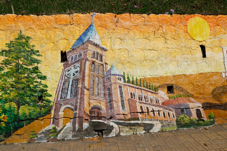 Bức họa giới thiệu Nhà thờ con Gà (Nhà thờ Chánh Tòa) Đà Lạt trên taluy đường Nguyễn Văn Trỗi (Phường 2, TP Đà Lạt)