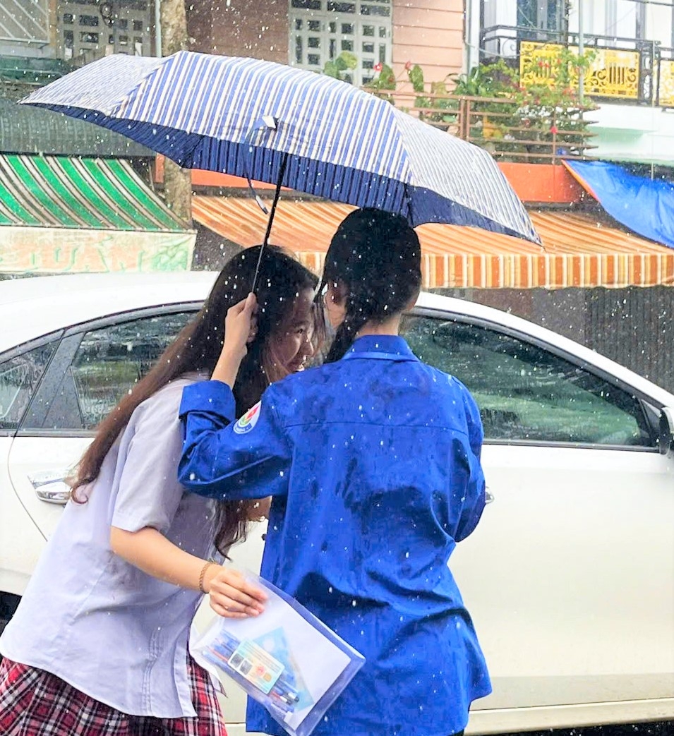 Lực lượng Thanh niên tình nguyện che dù cho thí sinh vào trường thi. (ảnh: Khánh Phúc)