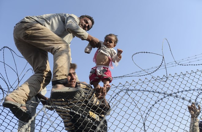 Người di cư Syria cố vượt qua hàng rào dây thép gai để vào lãnh thổ Thổ Nhĩ Kỳ ngày 14/6. (Nguồn: AFP/TTXVN)