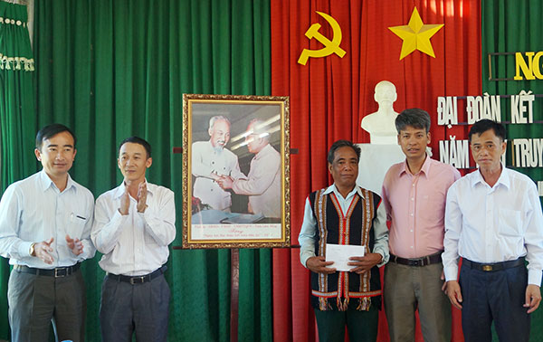 Ông Trần Văn Hiệp (thứ 2 từ trái qua) trao tặng nhân dân Bản B’Rum bức ảnh Bác Hồ với Bác Tôn - Ảnh: TRỊNH CHU
