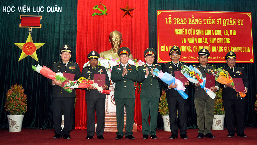 Thiếu tướng, TS Hoàng Văn Minh-Giám đốc Học viên Lục quân và Thiếu tướng Lê Anh Thơ-Chính ủy Học viên Lục quân trao bằng Tiến sĩ và tặng hoa chúc mừng các nghiên cứu sinh Cam-pu-chia
