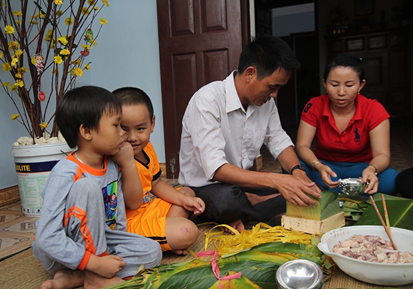 Các em nhỏ quây quần cùng ba mẹ gói bánh chưng. Ảnh: V.Q