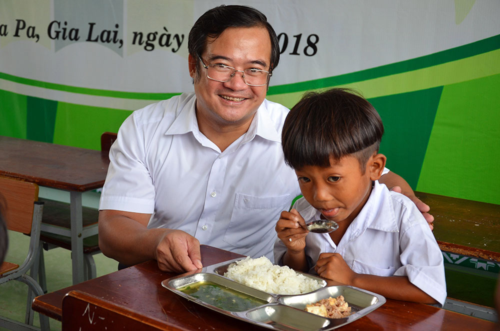 Ông Võ Anh Tuấn Bí thư huyện ủy Ia Pa với một học trò lần đầu tiên được dùng “Cơm Có Thịt” tại trường