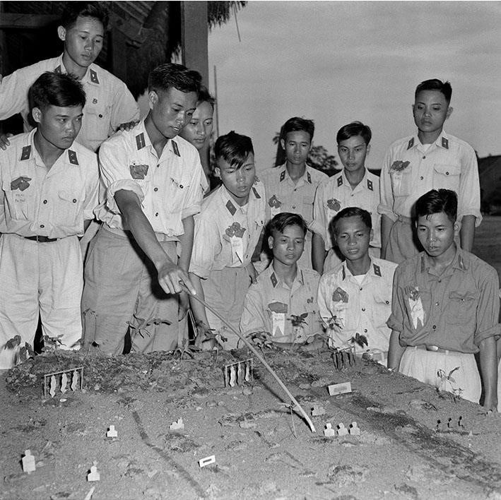 Tháng 6/1960, phong trào 'Cờ Ba nhất' được dấy lên từ Đại đội 2, Tiểu đoàn 10, Trung đoàn 68, Sư đoàn 304. Đây là đơn vị 'Ba nhất' đầu tiên trong toàn quân. Ngày 18/6/1960, Tổng cục Chính trị đã phát động phong trào thi đua 'Ba nhất' trong toàn lực lượng vũ trang. Trong ảnh: Hạ sỹ Phạm Ngọc Cương, lá cờ đầu trong phong trào thi đua chiến sỹ 'Ba nhất', Đại đội 3 (Sư đoàn 304) cùng các chiến sỹ 'Ba nhất' ôn tập bài mục trên sa bàn thao trường. (Ảnh: Đinh Quang Thành/TTXVN)