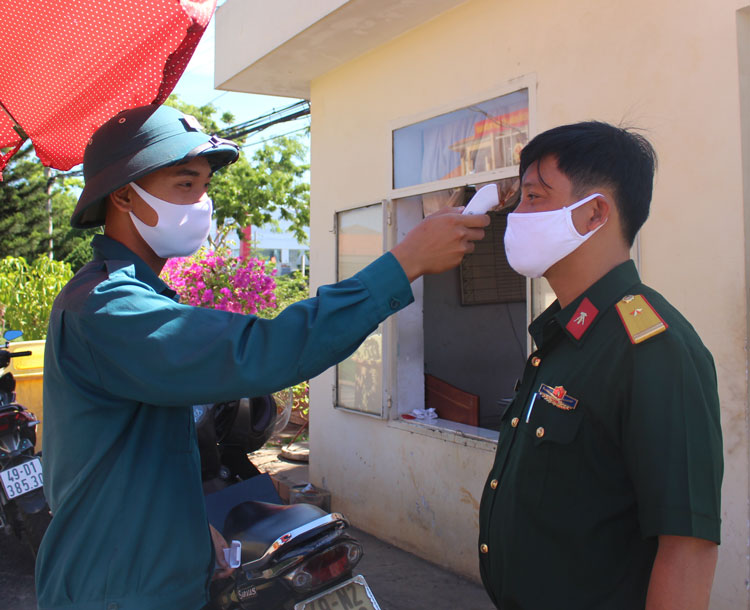 Bảo vệ UBND huyện Đức Trọng thực hiện đo thân nhiệt cho người đến liên hệ công tác