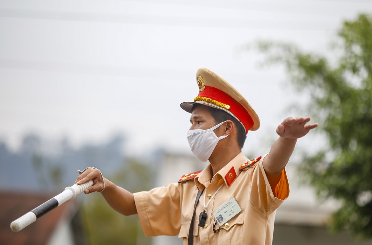 Lượng xe từ hướng đèo Sông Pha lên Lâm Đồng khá dày nhưng Thượng uý Trần Xuân Vinh, cán bộ Trạm Cảnh sát Giao thông chốt Eo Gió (thuộc Phòng Cảnh sát Giao thông Công an tỉnh Lâm Đồng) vẫn vui vẻ hướng dẫn các tài xế để xe đúng khoảng cách vào khu vực lều dã chiến dựng bên đường để khai báo y tế. Ảnh: C.T