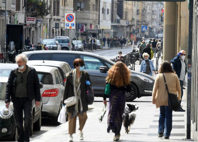 Người dân đeo khẩu trang phòng lây nhiễm COVID-19 trên đường phố tại Milan, Italy ngày 18/4/2020