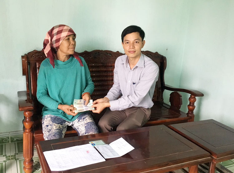 Cán bộ Phòng Lao động Thương binh và Xã hội huyện Đam Rông trao tiền tại nhà cho người có công huyện Đam Rông.