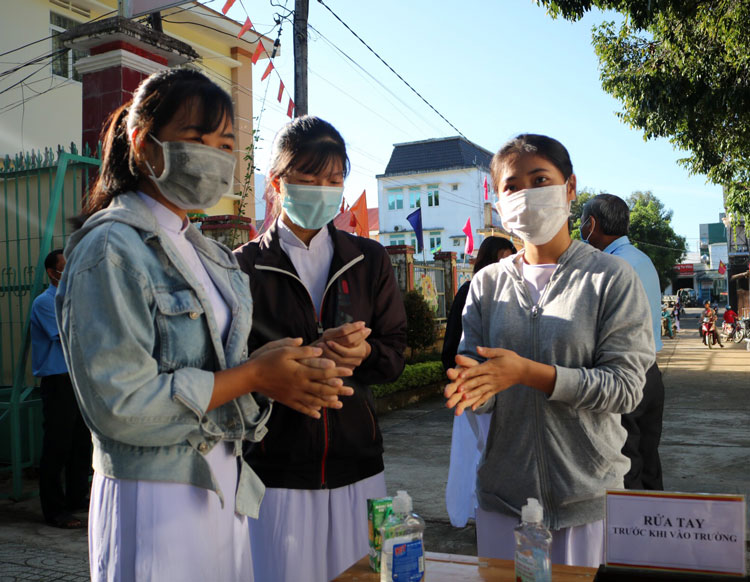 Các đại biểu, quý thầy cô giáo và các bạn học sinh sát khuẩn, đo thân nhiệt trước khi bước vào buổi lễ khai giảng