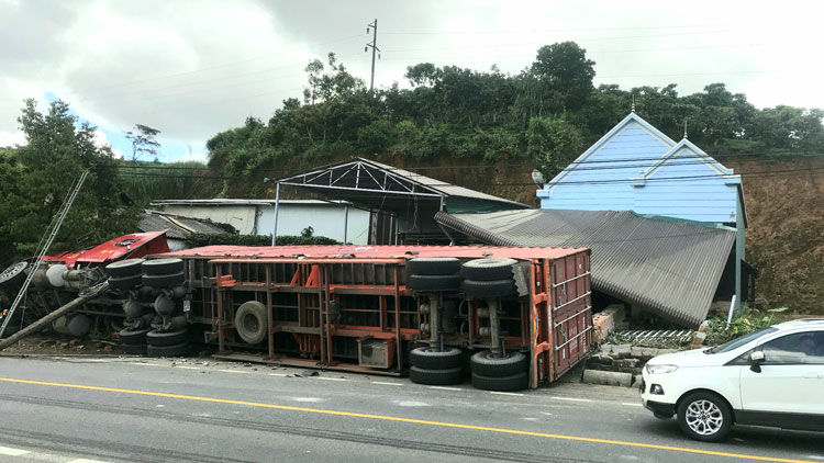 Xe container lật nghiêng ủi sập tường rào, mái che nhà dân