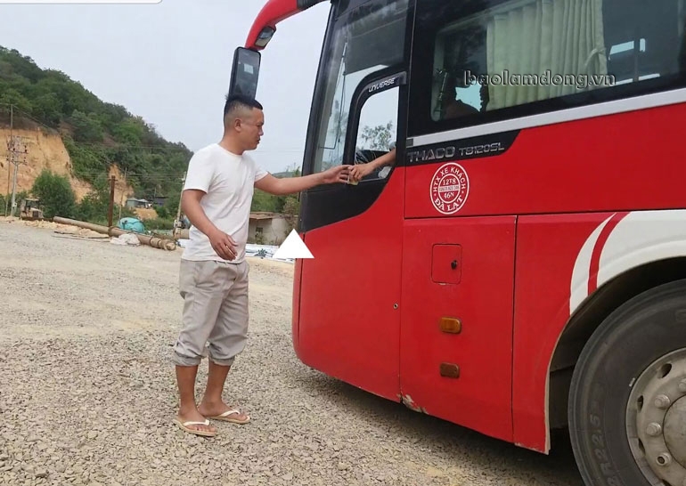 Người đàn ông nhận tiền từ chiếc xe khách giường nằm 45 chỗ để cho xe qua cầu vào sáng 19/1