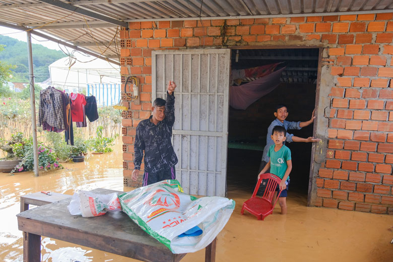 Ông Thạch Kha Minh (bên phải) nói 1 giờ sáng 9/7, nước dâng nhanh tới vị trí tay ông chỉ nên cả nhà phải chạy qua nhà hàng xóm tá túc qua đêm
