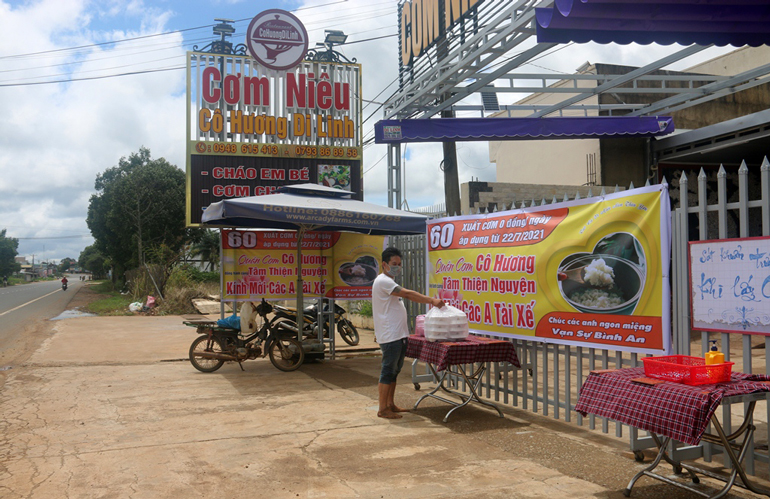 Tài xế đến nhận suất cơm tại bàn đặt trước cửa quán