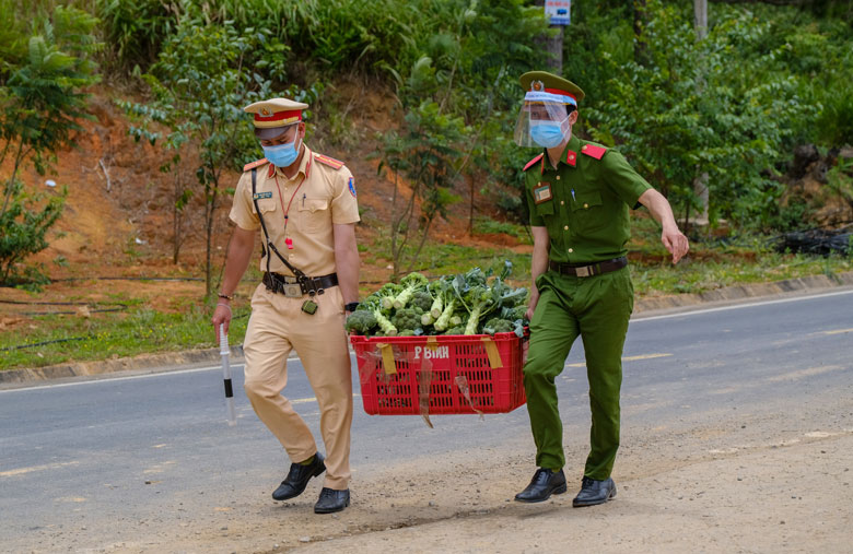 Lực lượng Công an phụ người dân vận chuyển nông sản tập kết tại chốt kiểm soát dịch Covid-19 trên Quốc lộ 20 để đưa vào tiêu thụ trên địa bàn xã Xuân Trường. Ảnh: Chính Thành 