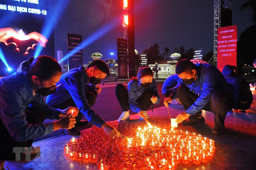 Tại Công viên Thống Nhất (Hà Nội), các đại biểu và nhân dân thắp nến tưởng niệm đồng bào và cán bộ, chiến sĩ hy sinh, tử vong trong đại dịch Covid-19. (Ảnh: TTXVN)