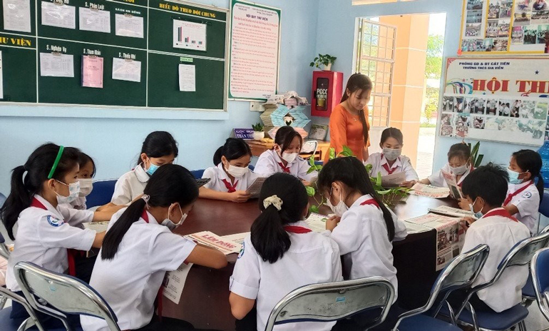 Cô Loan giới thiệu tờ báo địa phương với bạn đọc nhỏ tuổi