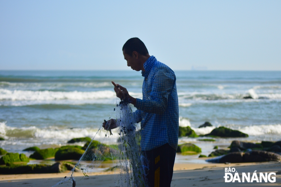 Người dân làng biển gỡ lưới cá bên ghềnh đá Nam Ô.